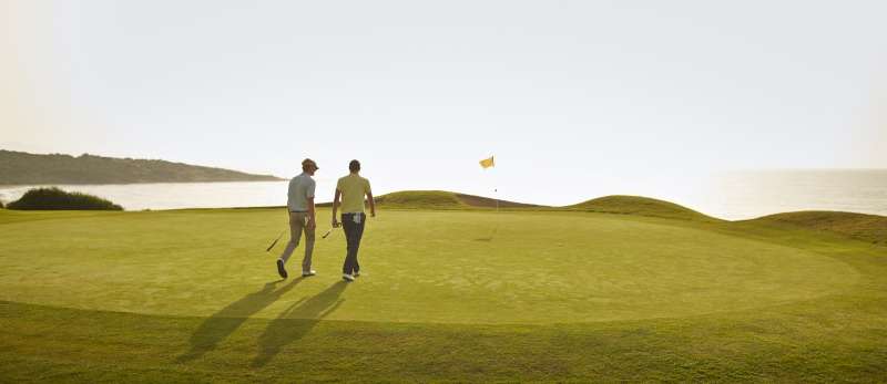 two men walking toward hole on golf course