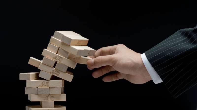 business person pulling piece out of jenga tower