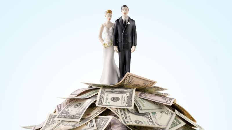 bride and groom wedding toppers on top of heap of cash