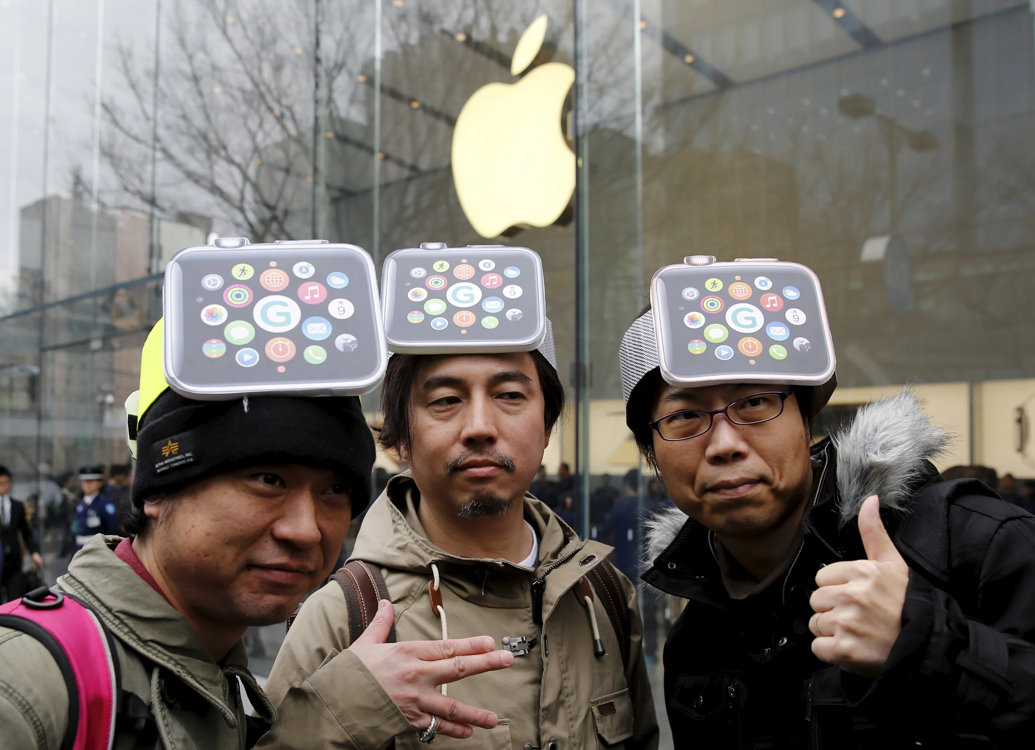 Men wearing cardboard Apple Watches on their heads pose for photos before it goes on display in front of the Apple Store in Tokyo's Omotesando shopping district.