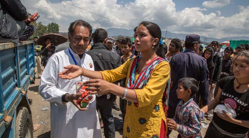 Volunteers give out packages of instant noodles to residents living in an evacuation area in Tundhikel park on April 27, 2015 in Kathmandu, Nepal.