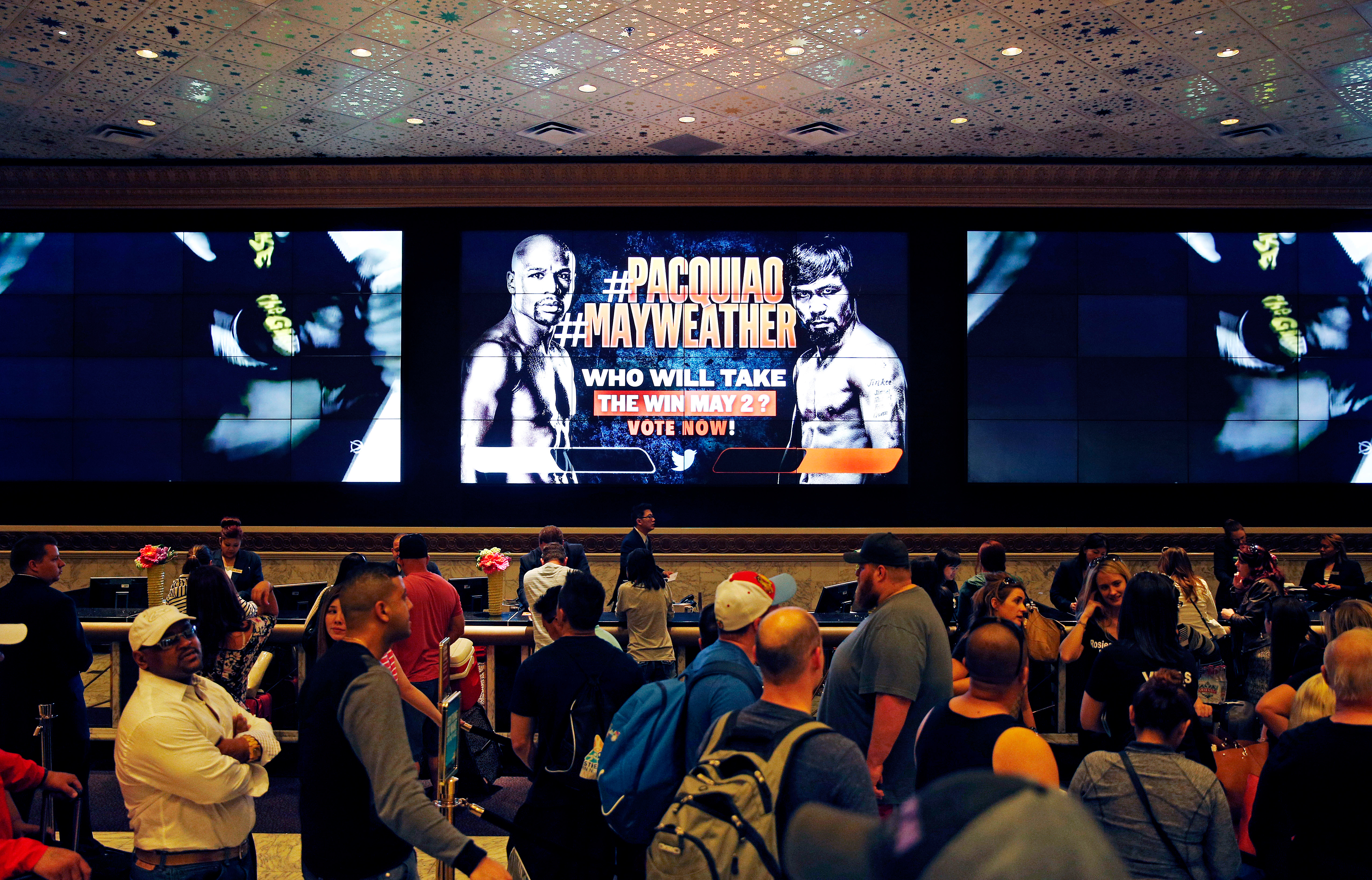 An advertisement for a fight between Floyd Mayweather Jr. and Manny Pacquiao is seen on a screen as people wait to check in at the MGM Grand Friday, April 24, 2015, in Las Vegas. The fight is scheduled to take place May 2 at the hotel and casino.
