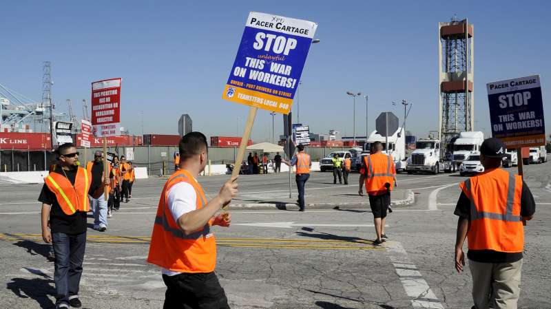 Striking trucker drivers and members of the International Brotherhood of Teamsters walk the picket line at the Port of Long Beach in California, United States April 27, 2015. Tractor-trailer drivers who haul freight from the ports of Los Angeles and Long Beach went on strike on Monday against four trucking companies, a Teamster union official said, in a move that could revive labor tension at the nation's busiest cargo hub. The port drivers accuse the trucking companies of wage theft by illegally misclassifying them as independent contractors, deducting truck-leasing charges and other expenses from their paychecks. The truckers are demanding to be reclassified as company employees with the right to union representation.