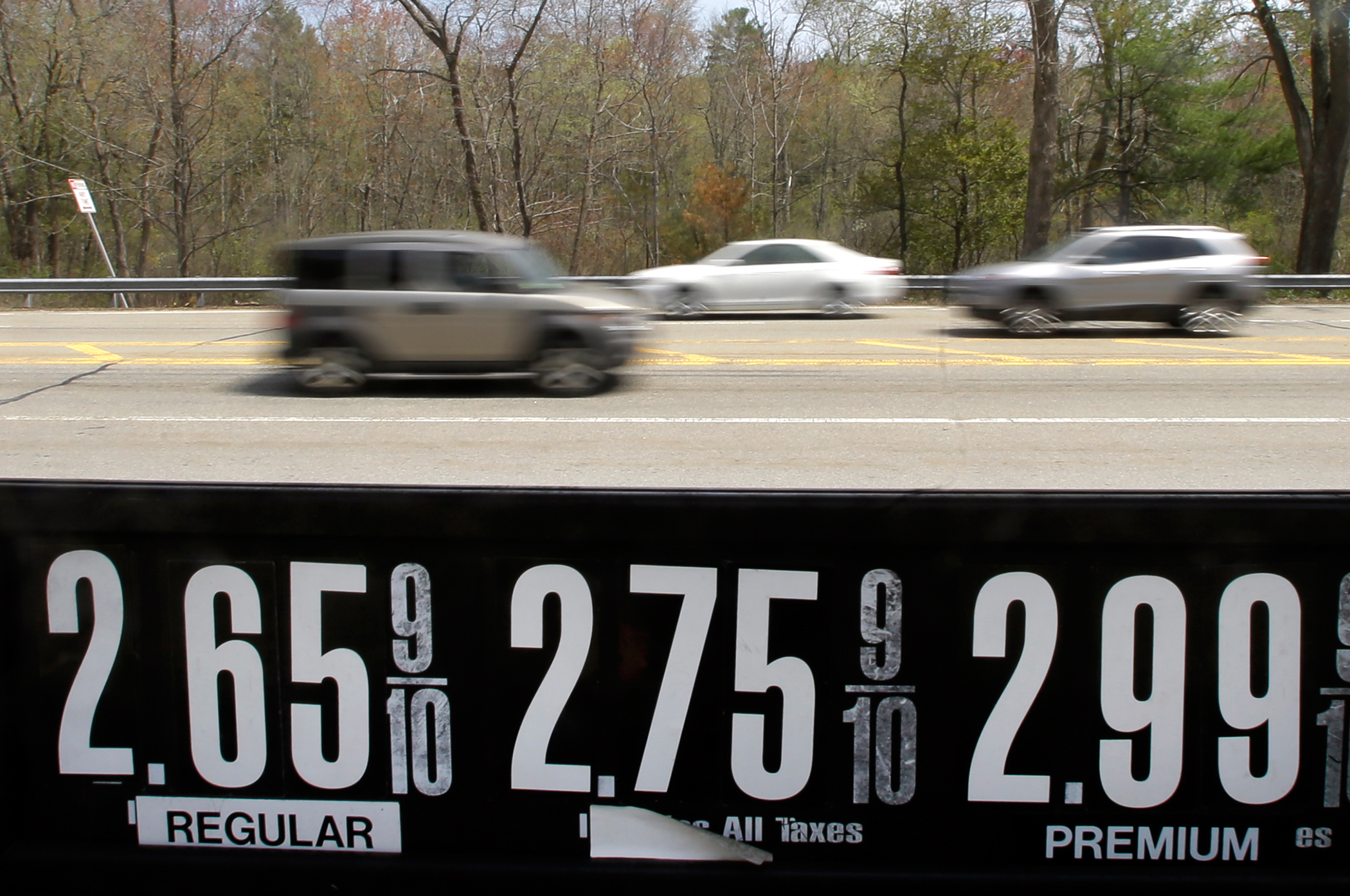 In this May 8, 2015 photo, vehicles drive past a gas station in Andover, Mass. Even after the typical springtime run-up, the average price for gallon of regular gasoline should top out around $2.60.