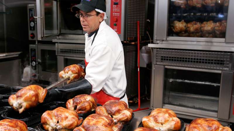 A Costco butcher spreads out roasted chicken at Costco in Mountain View, California.