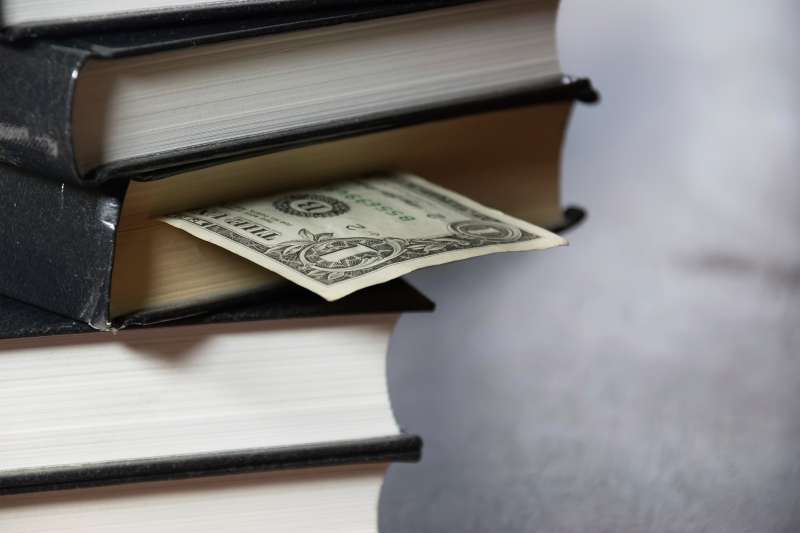 dollar bill shoved in pile of books