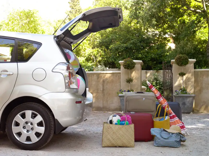 overstuffed SUV trunk with vacation luggage sitting on pavement