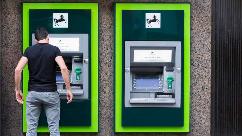 A customer uses an automated teller machine (ATM) outside a Lloyds Bank branch, a unit of Lloyds Banking Group Plc, in London, U.K., on Tuesday, May 12, 2015. The U.K. government sold about 634 million pounds ($987 million) of shares in Lloyds Banking Group Plc, cutting its stake to less than 20 percent a week after elections. Photographer: Jason Alden/Bloomberg