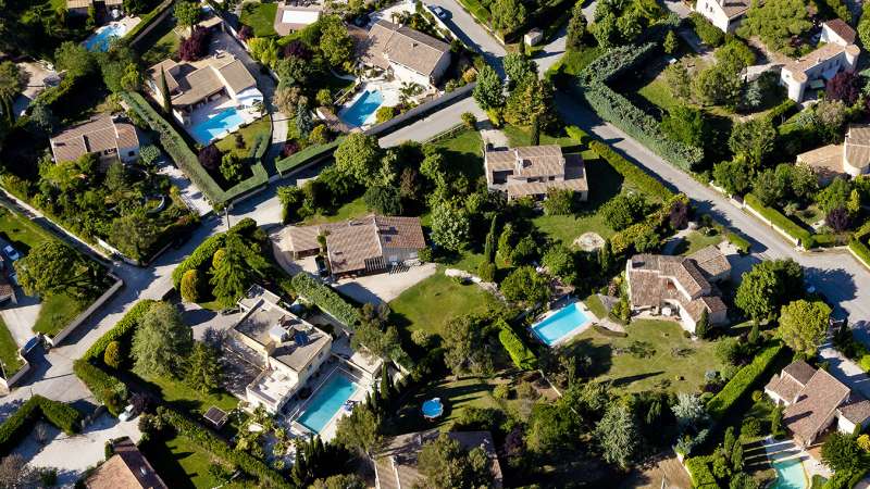 aerial view of homes with green lawns and pools