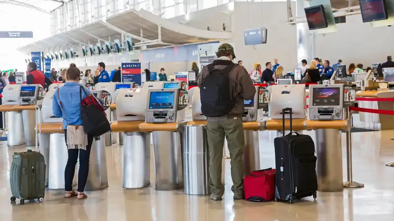 Passengers use self-service machines to check in for flights on Delta Air Lines at Detroit Metro Airport.