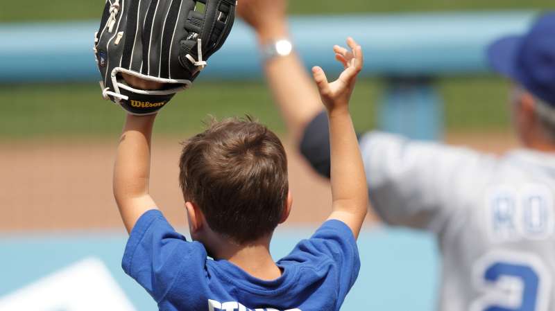 A young fan holds up a glove in hopes of catching a baseball as his father holds him on his shoulders during the Los Angeles Dodgers Father's Day game against the Houston Astros on June 19, 2011 at Dodger Stadium in Los Angeles, California.