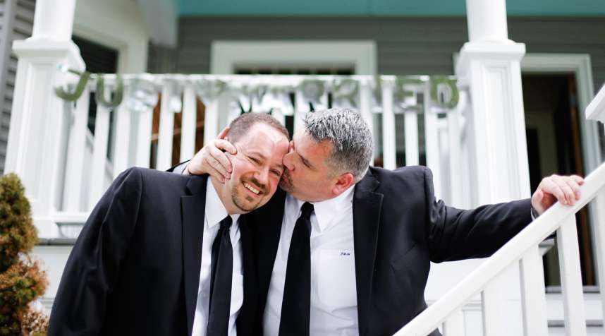 Jay Norris gives his partner, Doug Fillmore, a kiss under a Just Married sign their neighhbors put up for them at their home on the Eastern Promenade in Portland, Maine.