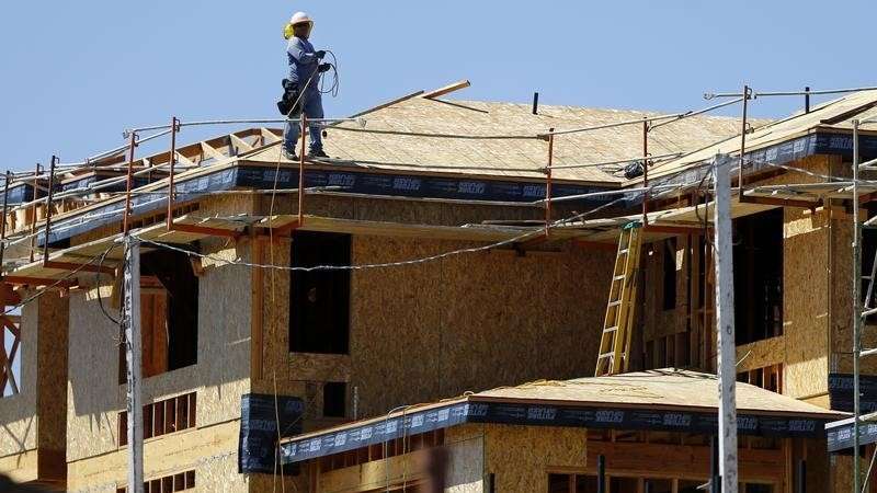 A worker walks on the roof of a new home under construction in Carlsbad