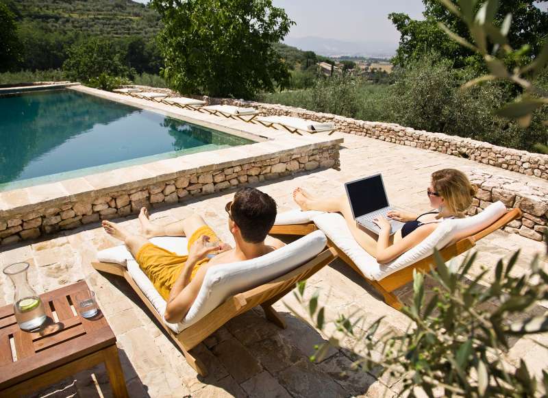 couple by the pool, woman on laptop