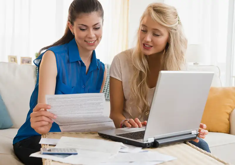 Roommates looking over bills with laptop computer