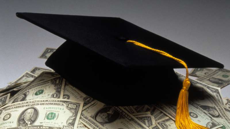 graduation cap mortarboard on top of pile of cash