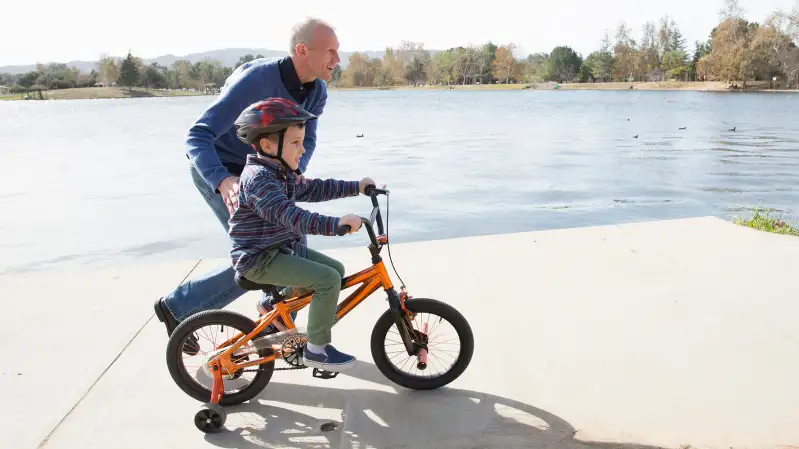 senior adult teaching child to ride bike