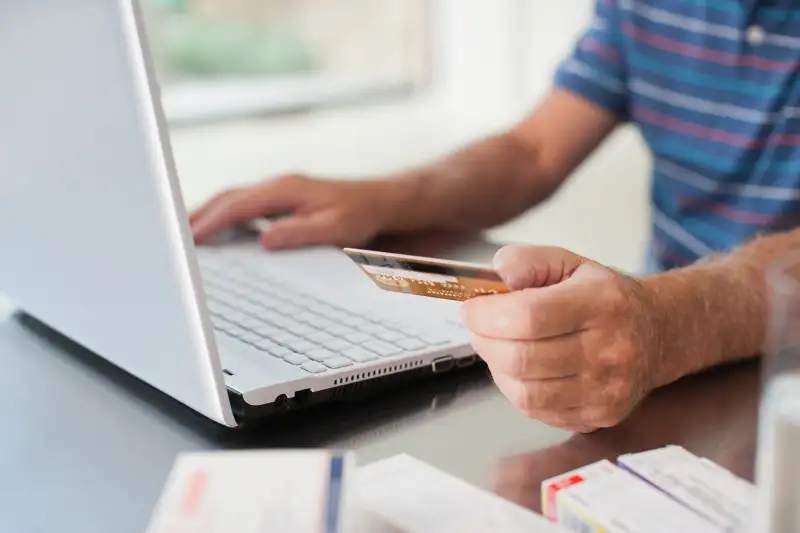 man using credit card to make online payment on laptop