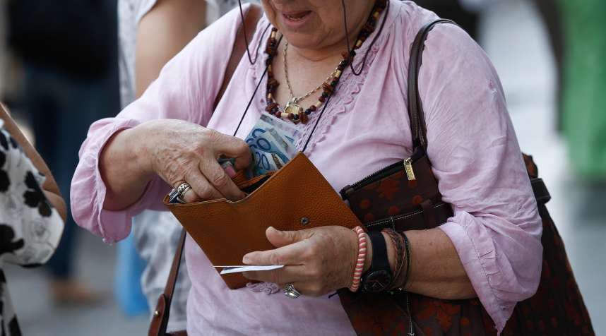 A customer places her daily cash machine withdrawal limit of 60 euros into her purse after using an automated teller machines (ATM) outside a closed Eurobank Ergasias SA bank branch in Athens, Greece, on Monday, June 29, 2015.