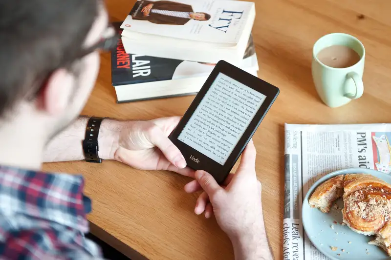 man holding amazon kindle in cafe