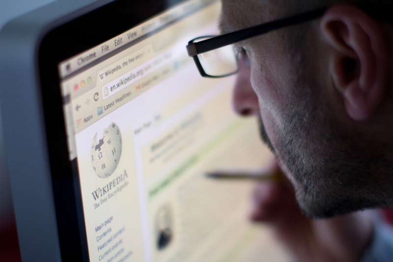 man editing Wikipedia page on computer screen
