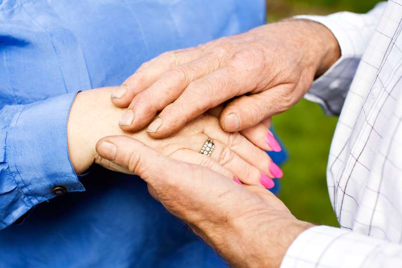 senior man and woman holding hands, diamond ring on woman's hand