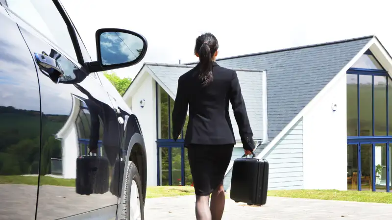 woman in business suit walking from car to house