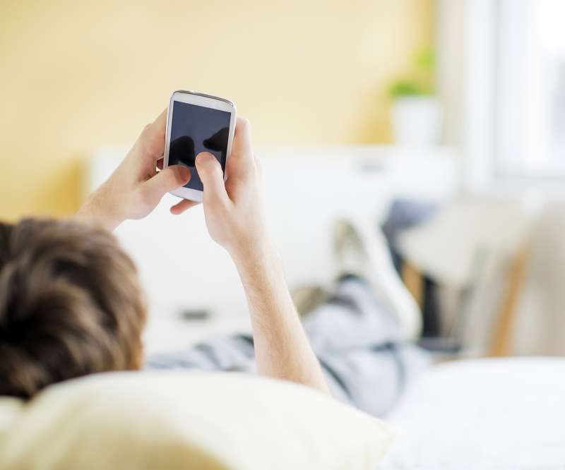 person texting on smartphone from bed