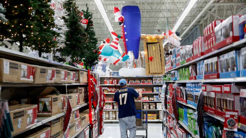 A shopper walks through an aisle of Christmas trees and lights displayed for sale at a Wal-Mart Stores Inc. in Los Angeles, California on November 24, 2014.