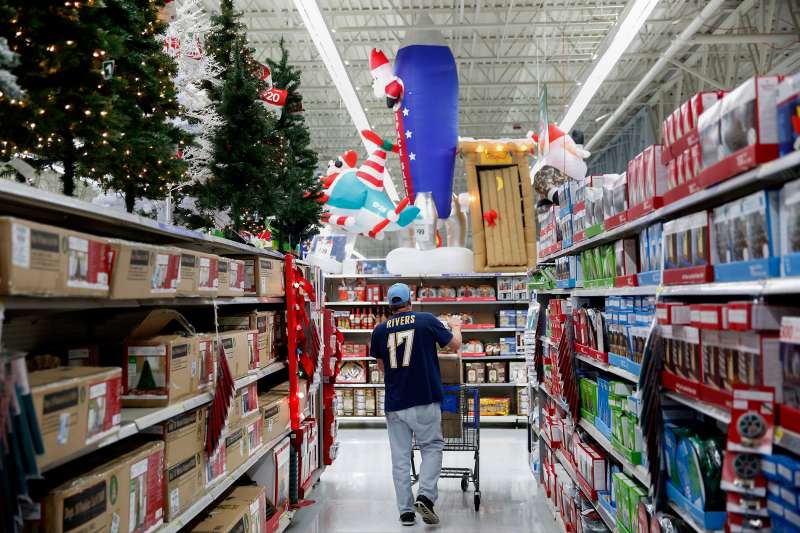 A shopper walks through an aisle of Christmas trees and lights displayed for sale at a Wal-Mart Stores Inc. in Los Angeles, California on November 24, 2014.