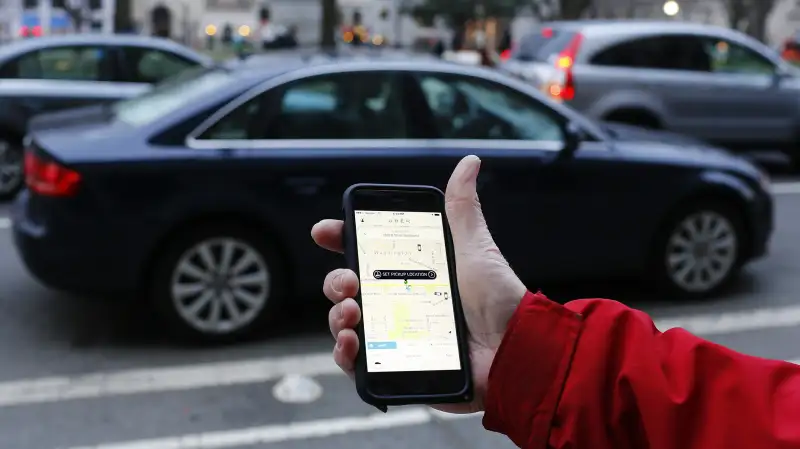 person using Uber app on mobile with car in background