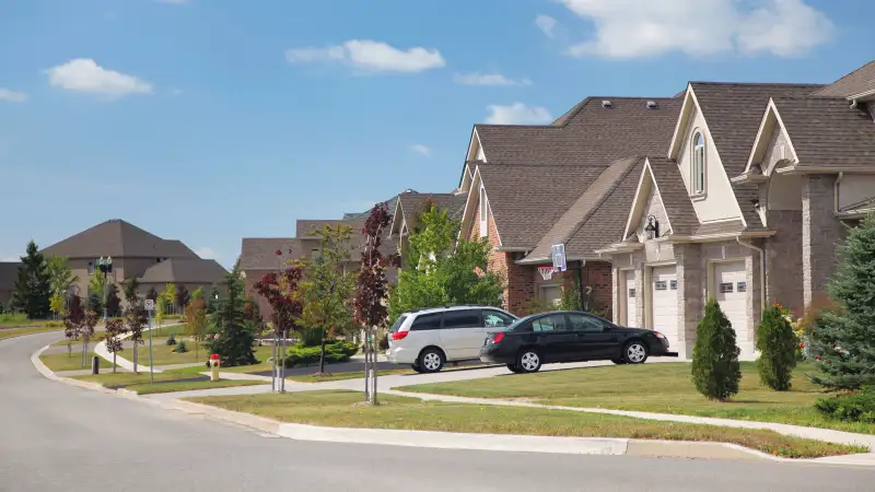 suburban street with cars in driveway of houses