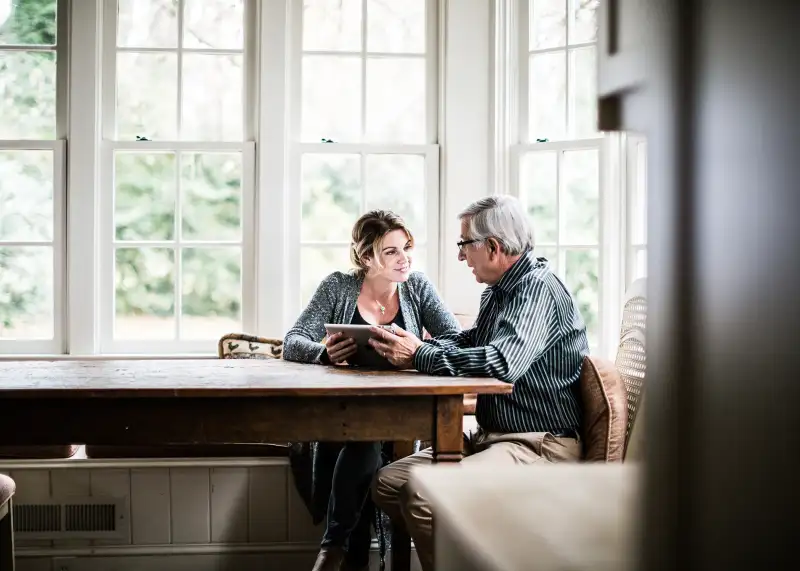 adult woman talking to elderly man in kitchen