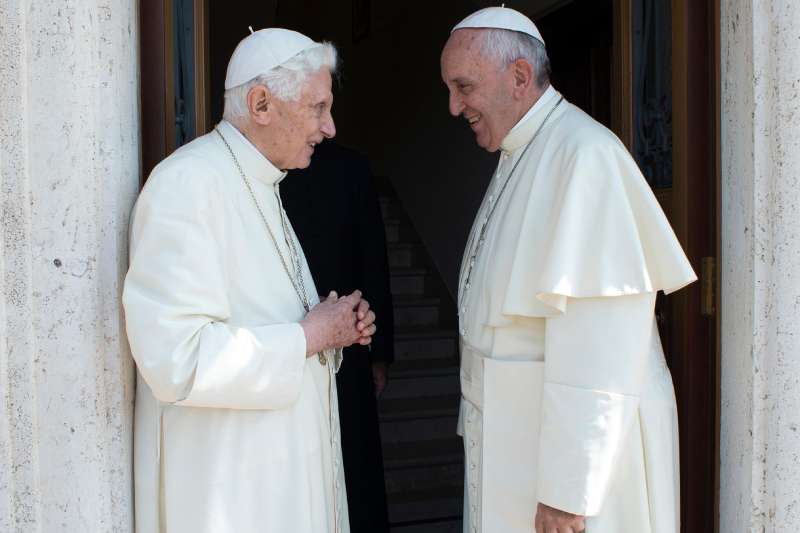 Pope Francis, right, greets Emeritus Pope Benedict XVI, at the Vatican, June 30, 2015. Emeritus Pope Benedict XVI is leaving the Vatican for his first sojourn since retiring.