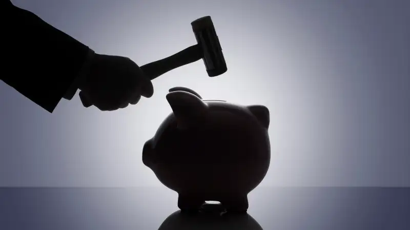 silhouette of hammer coming down on piggy bank