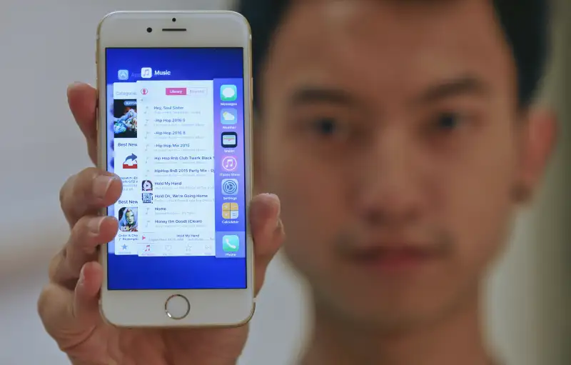 A sales assistant shows features of iOS 9 on an Apple iPhone 6 at an Apple reseller shop in Bangkok, September 18, 2015.