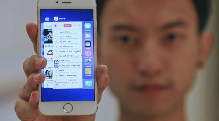 A sales assistant shows features of iOS 9 on an Apple iPhone 6 at an Apple reseller shop in Bangkok, September 18, 2015.