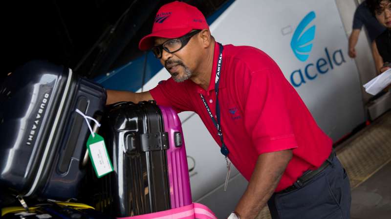 An Amtrak red cap baggage handler pushes a cart next to an Amtrak Acela passenger train at Union Station in Washington, D.C., U.S., on September 3, 2015.