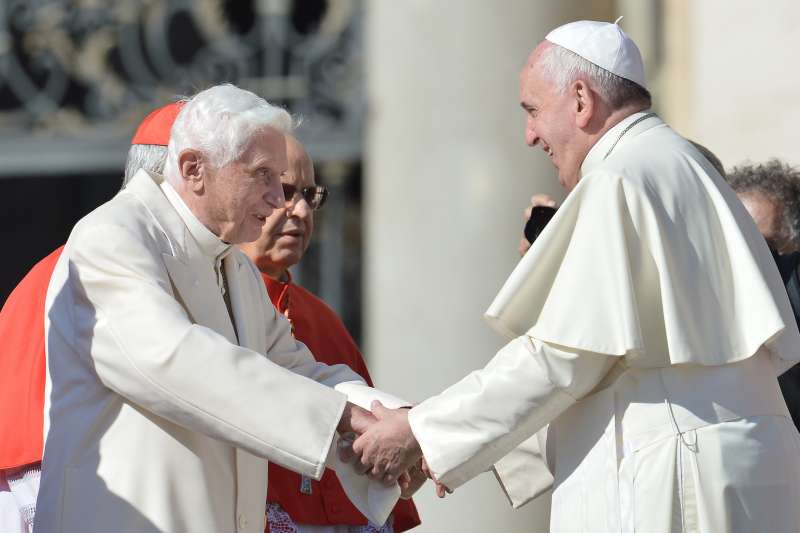 Pope emeritus Benedict XVI speaks with Pope Francis during a papal mass for elderly people at St Peter's square on September 28, 2014.