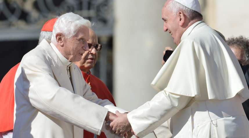 Pope emeritus Benedict XVI speaks with Pope Francis during a papal mass for elderly people at St Peter's square on September 28, 2014.