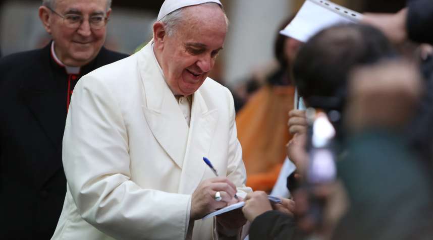 Pope Francis signs an autograph as he visits Roman Parish of Sacro Cuore di Gesu on January 19, 2014.