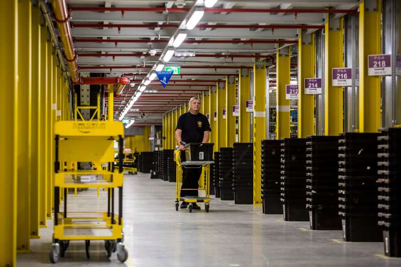 An employee wheels a cart past product storage bays on the opening day of the new Amazon.Com Inc. fulfillment center in Dobroviz, Czech Republic, on Tuesday, Sept. 8, 2015. By the year 2018, 2,000 permanent and 3,000 seasonal workers will find a job at the warehouse which already now has 1,500 permanent employees. Photographer: Martin Divisek/Bloomberg