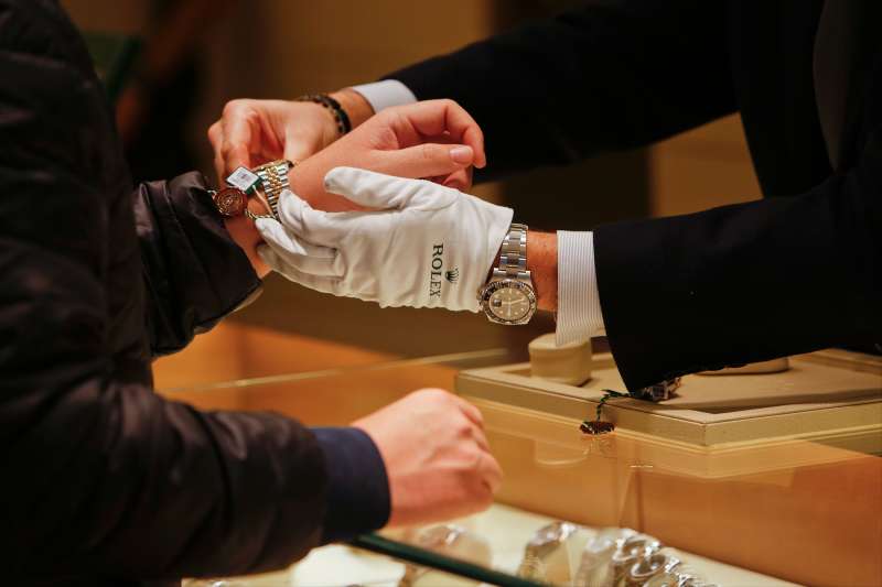 A salesman fits a Rolex Group watch onto a customer's wrist at the GEARYS Rodeo Drive Rolex store in Beverly Hills, California, on December 9, 2013.