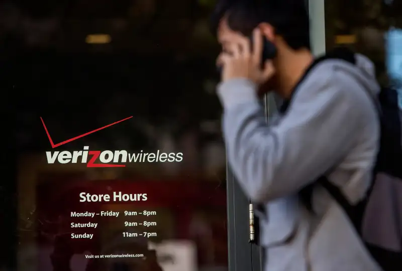 A pedestrian talks on his mobile phone while walking past a Verizon Wireless store in San Francisco, California, on April 15, 2015.