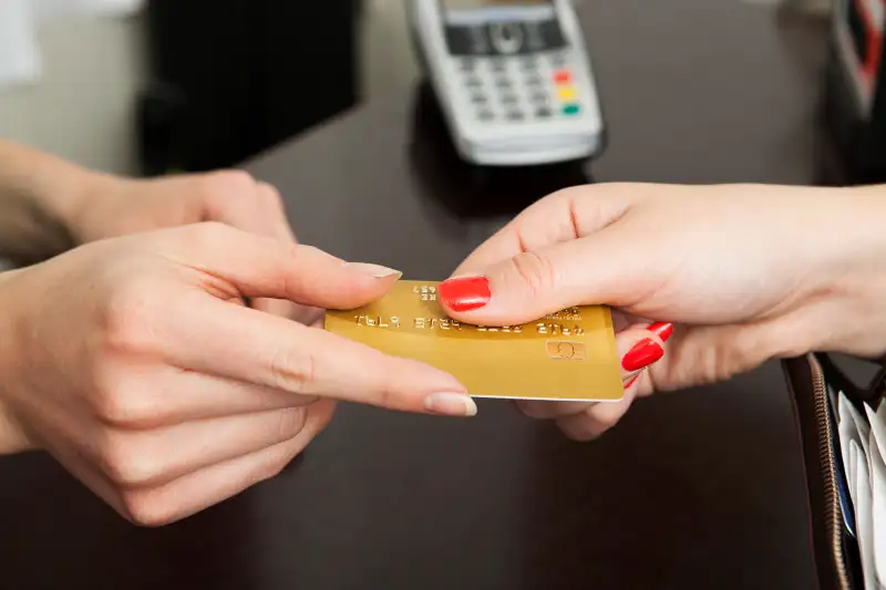 Woman handing over credit card for payment.