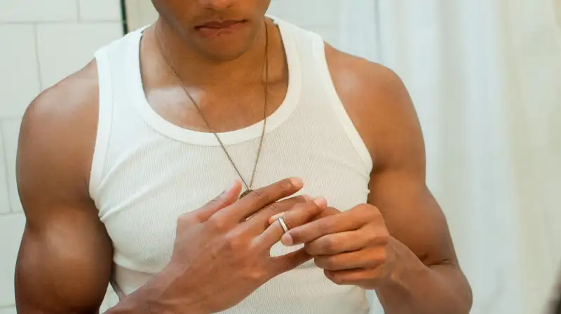 man removing wedding ring in bathroom