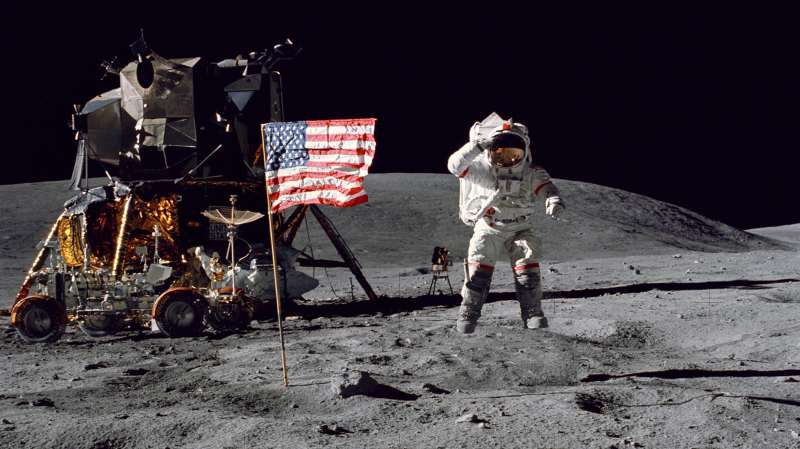 Astronaut John W. Young, commander of the Apollo 16 lunar landing mission, leaps from the lunar surface as he salutes the United States flag at the Descartes landing site near Stone Mountain during the first Apollo 16 extravehicular activity (EVA), April 16, 1972. The Lunar Module  Orion  is at the left with the Lunar Roving Vehicle is parked beside it.