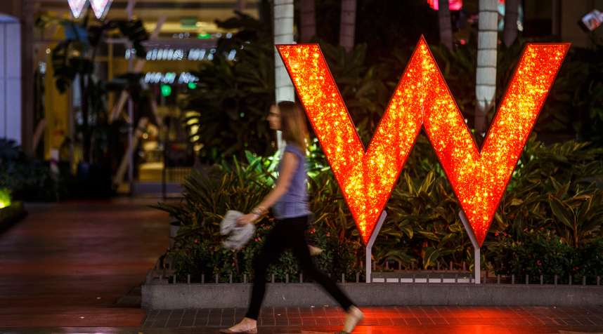 A woman walks past signage displayed outside of the W Hotel Hollywood in Hollywood, California, on October 26, 2015.