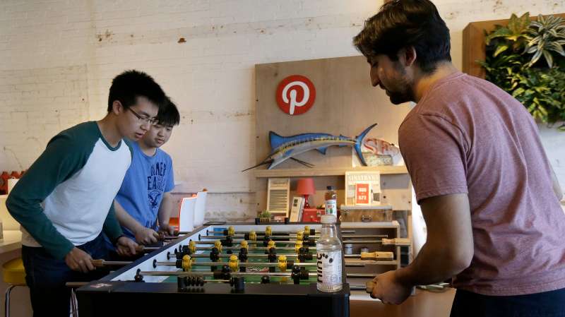 Pinterest software engineer interns Kevin Lau, from left, Charlie Gu and Neil Raina play foosball in the office in San Francisco, Wednesday, April 1, 2015. The San Francisco-based venture capital darling celebrated its fifth birthday in March 2015.