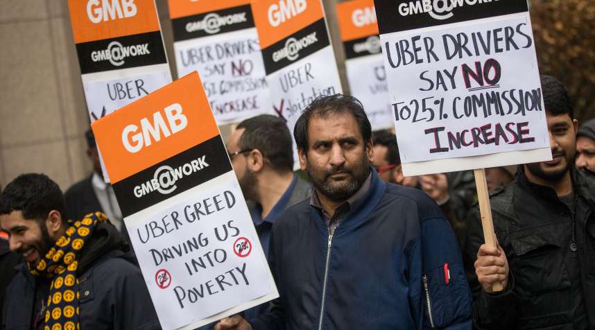 Uber drivers hold up signs during a protest against a rise in the commission taken by Uber.